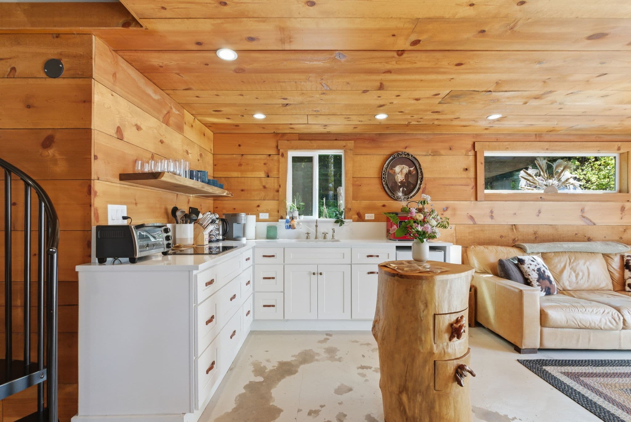 Cottage kitchen with spiral staircase to the loft, white cabinets, and pine ceiling