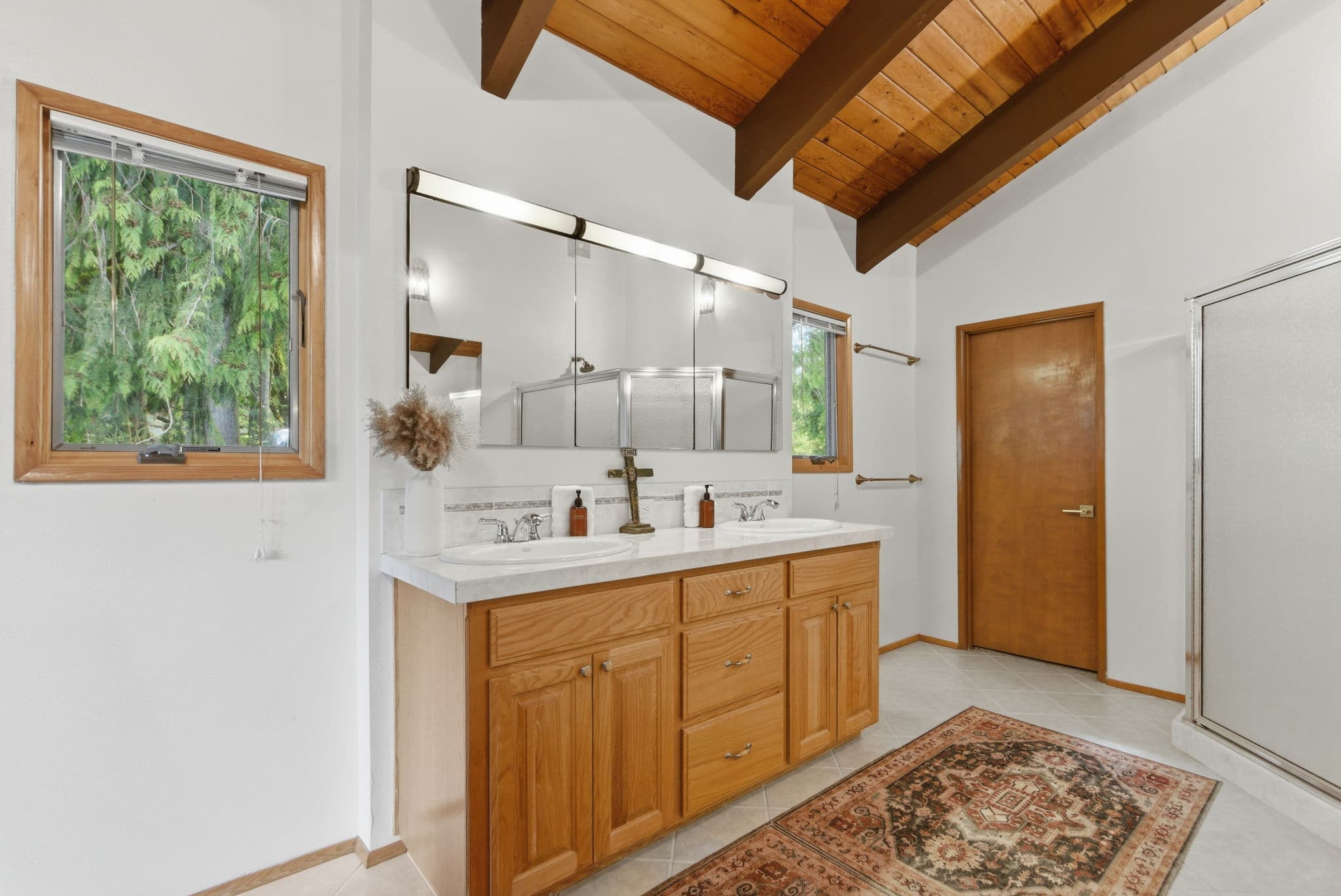 Guest bath with a vaulted wood-beam ceiling and glass shower stall