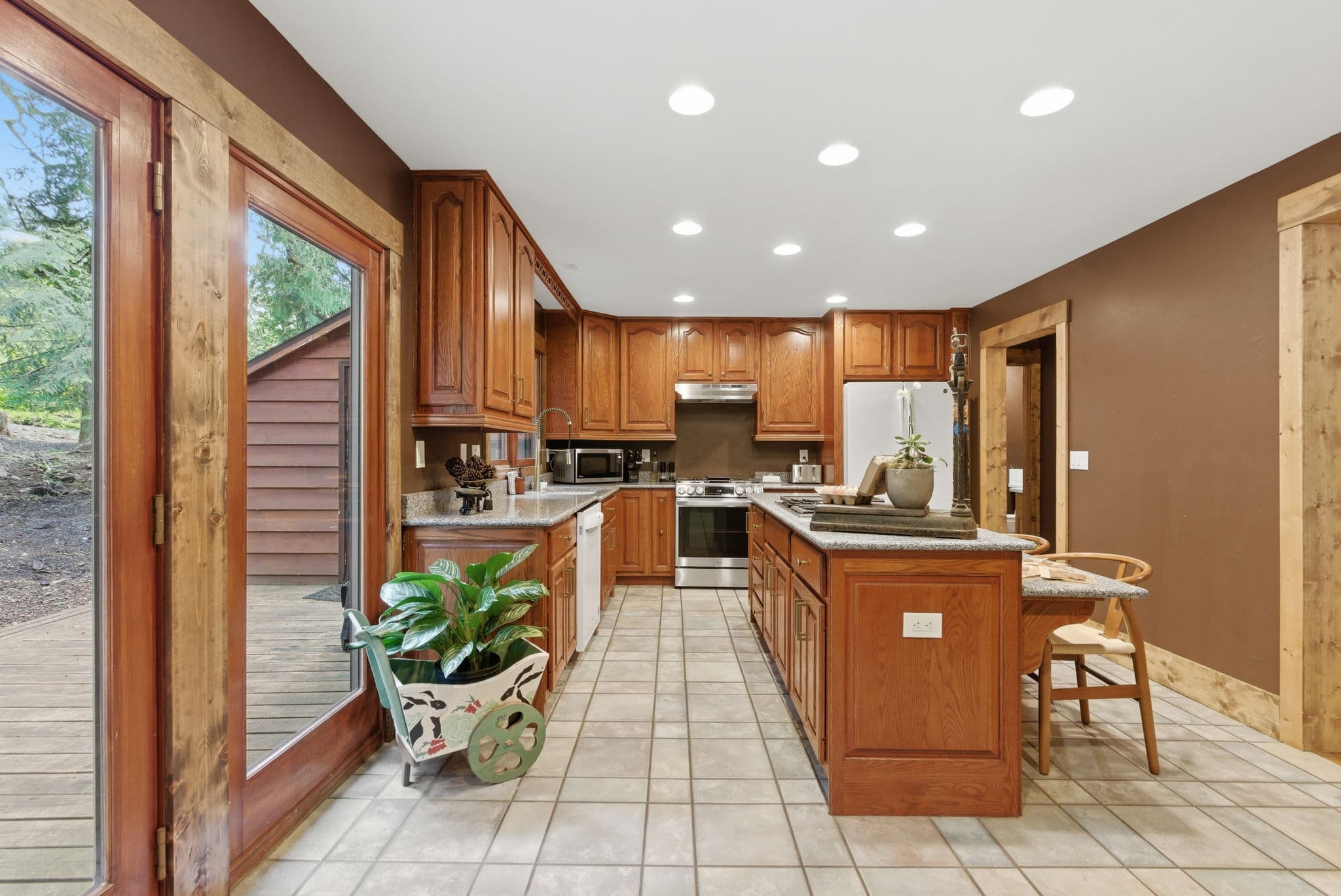 Full kitchen with oak cabinets, a granite island and French doors to the deck