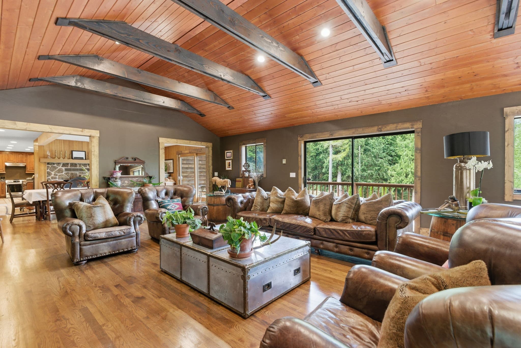 Living room with Chesterfield sofas, curved iron-truss ceiling, and stone fireplace