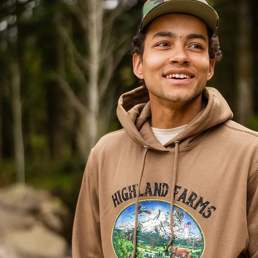 Wearing the Dream hoodie in coyote brown, outdoors among trees