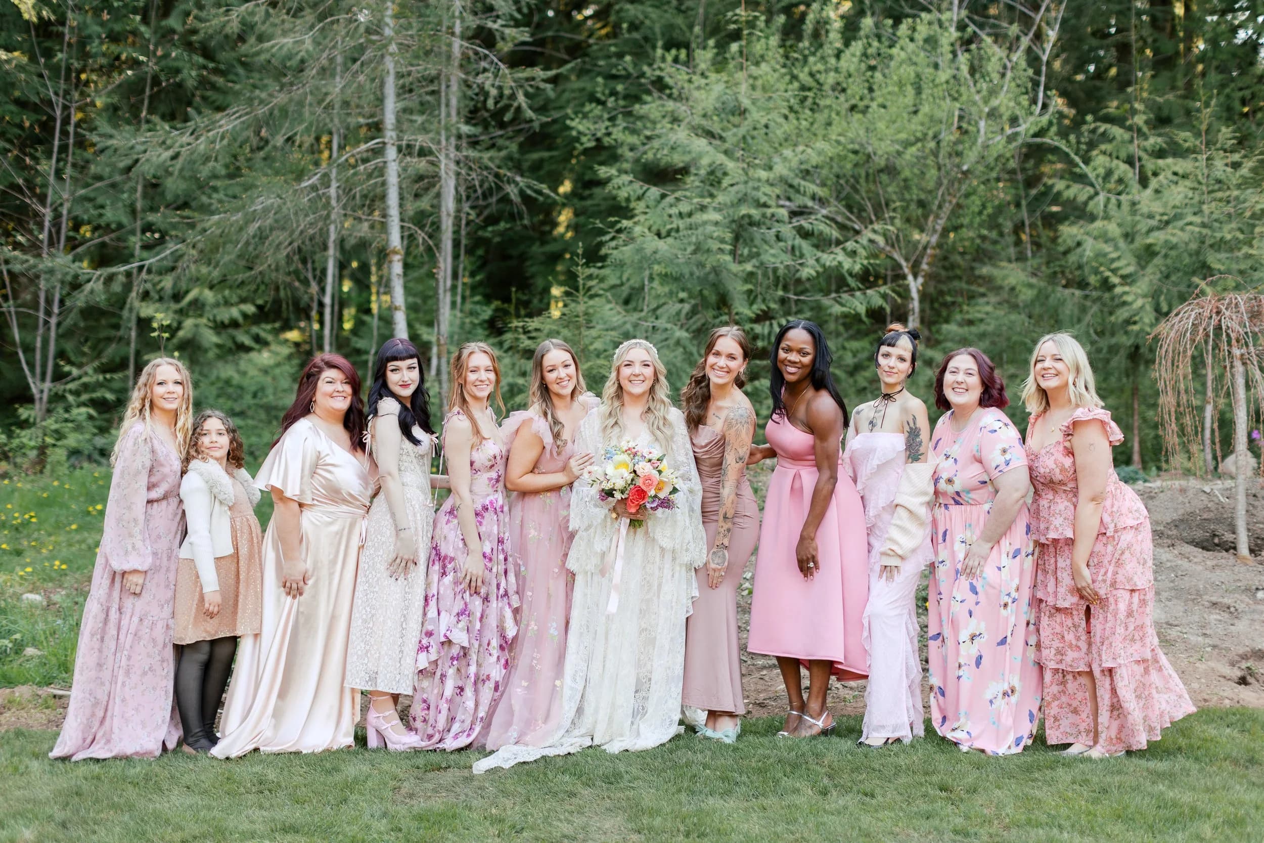 Bridesmaids in every shade of pink stand together on the lawn