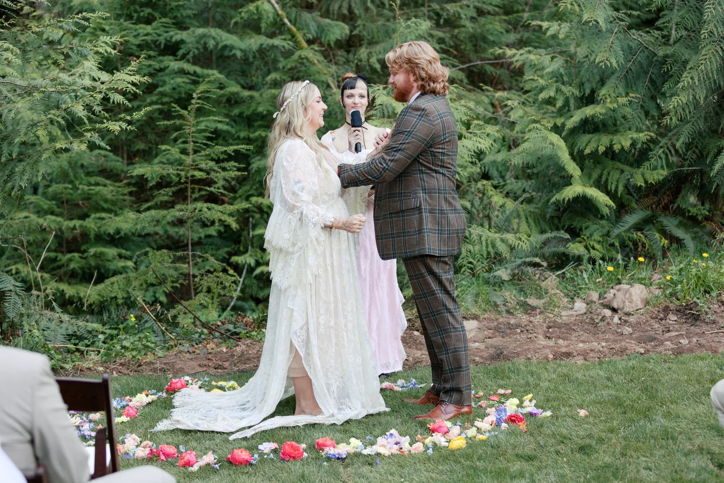 A couple exchange vows inside a ring of flower petals on the lawn